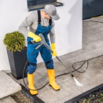 Caucasian Men Pressure Washing His House Surrounding Using Powerful Washer. Small Architecture Cleaning.