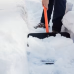 Snow removal. Man clearing snow by shovel after snowfall. Outdoors.